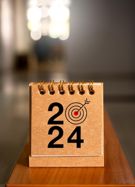 Happy new year 2024 banner background 2024 numbers year with target icon on beige small desk calendar cover standing on wood table vertical minimal style Business goals plan and success concepts