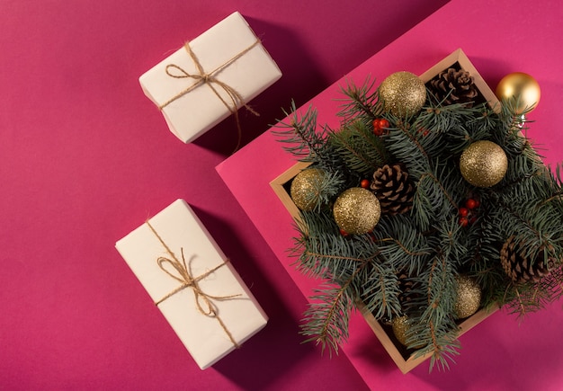 Happy New Year card or banner with gift boxes on a purple background decorated with festive fir tree branches.