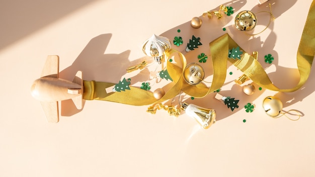 Happy new year and Merry christmas. Wooden children's plane with christmas elements and satin ribbon on a beige background