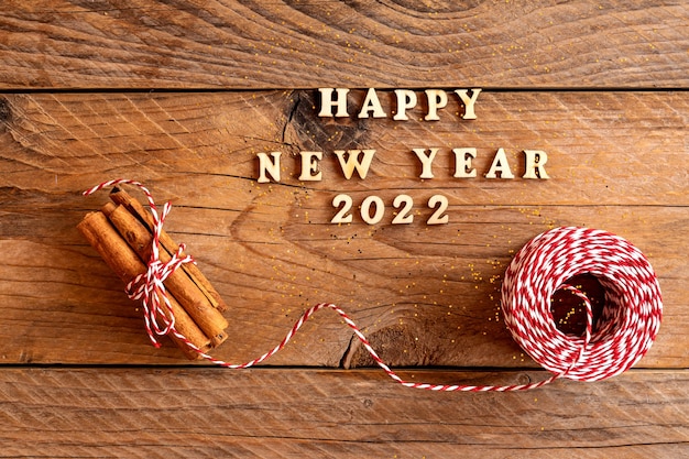 Happy new year quotation made with wooden letters decorated with cinnamin sticks and red and white cord. Festive new year background