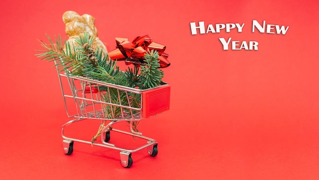 Happy New Year. Small shopping trolley with fir branches, gift bow and gingerbear.