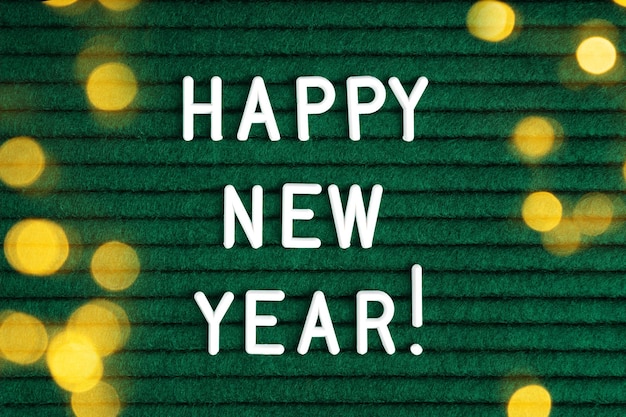 Photo happy new year , text on green felt letter board with white letters and light effect bokeh . top view, flat lay