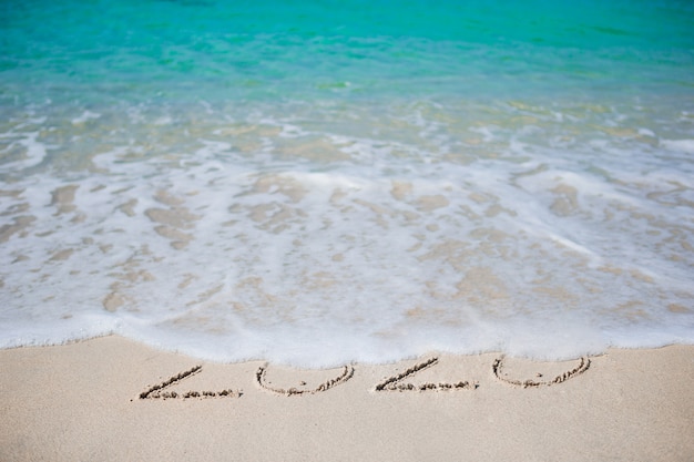 Happy New Year written in the white sand