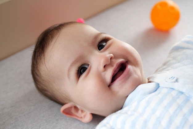 Happy newborn baby makes a funny face Portrait of a crawling baby in his room close up