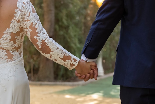 Happy newly married couple holding hands walking in a park