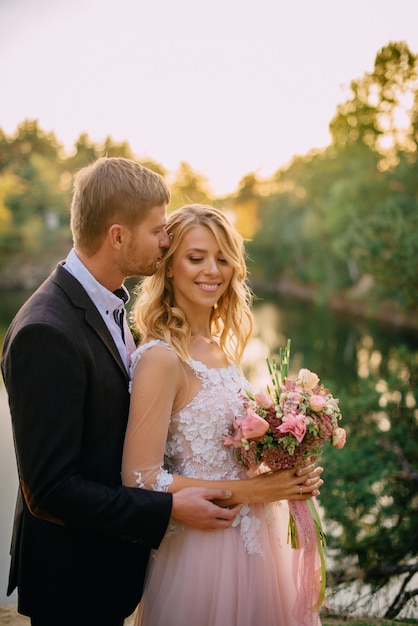 Happy newlyweds standing at sunset