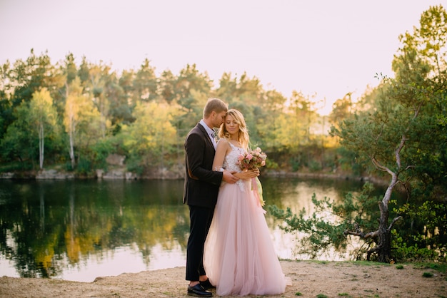 Happy newlyweds standing at sunset