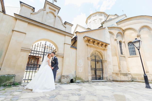 Happy newlyweds walk holding hands along an old street of a European city on a beautiful architecture