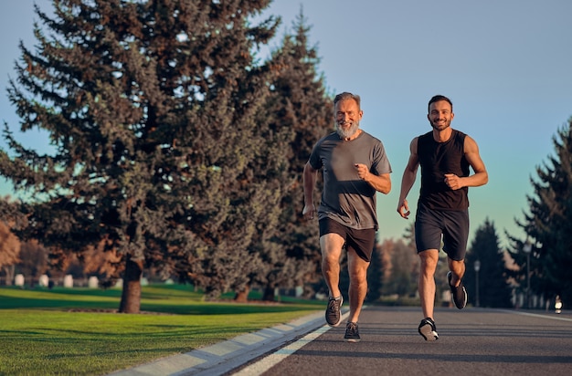 The happy old and young sportsmen running on the road