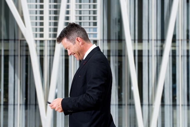 Happy older businessman holding mobile phone