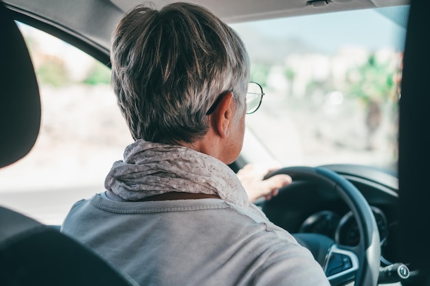 Happy owner Handsome mature woman sitting relaxed in his newly bought car looking at the road smiling joyfully One old senior driving and having funxA