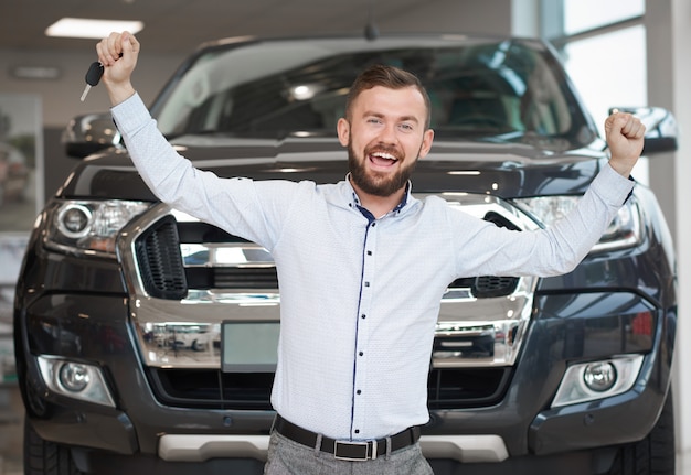 Happy owner of new black jeep smiling and holding hands up.