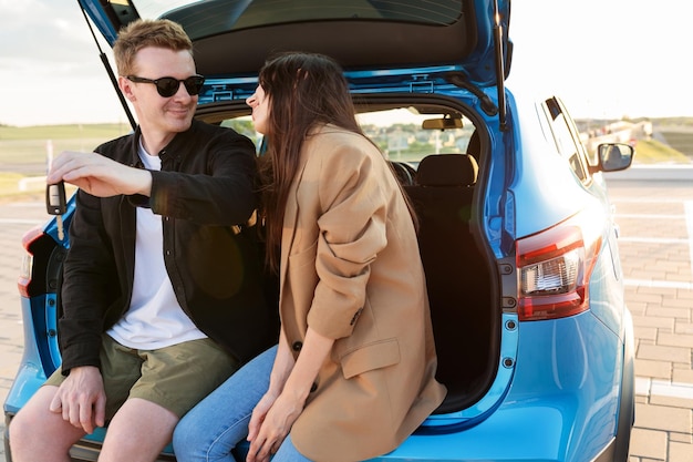 Happy owners of a new car A man and a young woman are sitting in a new car Outside