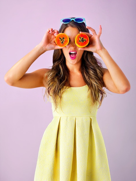 Photo happy papaya on eyes and woman in studio for healthy eating nutrition and detox for wellness food smile and person with fruit for organic diet wellbeing and natural vitamins on pink background