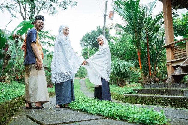 Happy parent and daughter going to the mosque or a field to do idul fitri or eid mubarak prayer