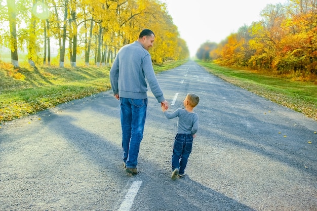 A Happy parent with child are walking along the road in the park on nature travel