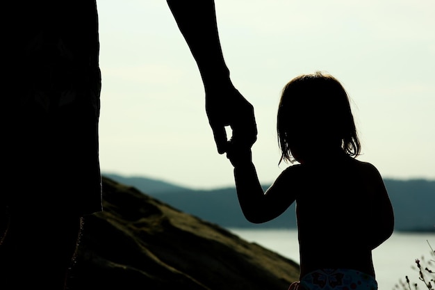 happy parent with child in nature by the sea silhouette