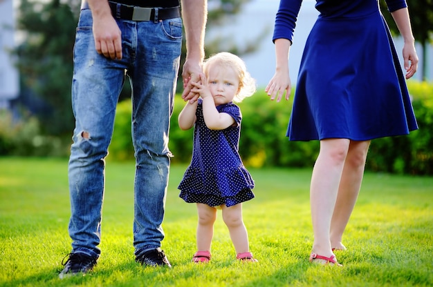 Happy parenthood: young parents with their sweet toddler girl in sunny park.