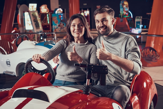 Happy parents in amusement park sitting on toy car