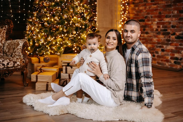 Happy parents celebrate Christmas with their beloved son in a beautiful cozy atmosphere at home.