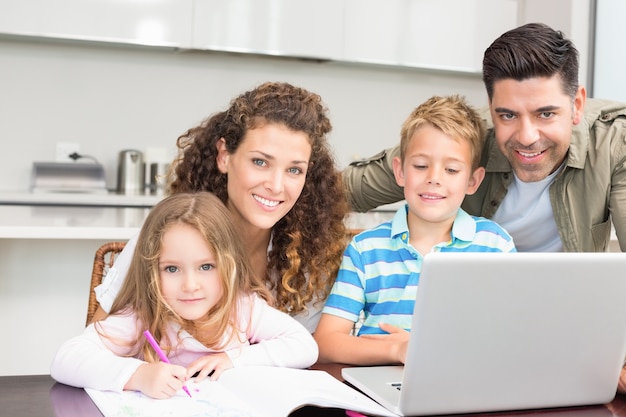 Happy parents colouring and using laptop with their children