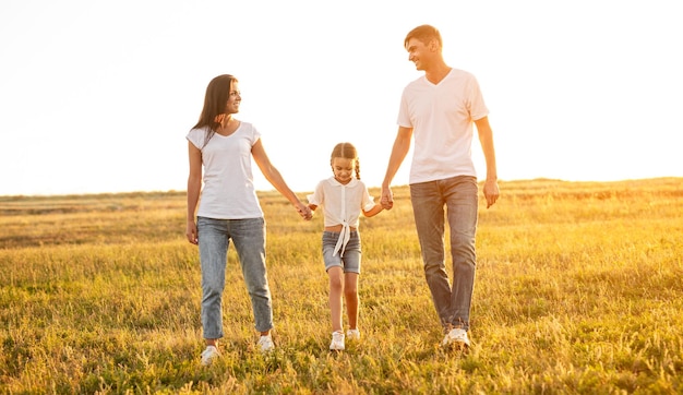 Happy parents walking with daughter in field