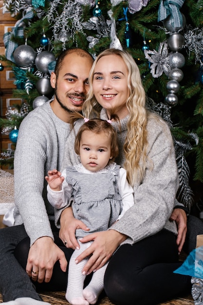 Happy parents with baby in decorated room for Christmas.