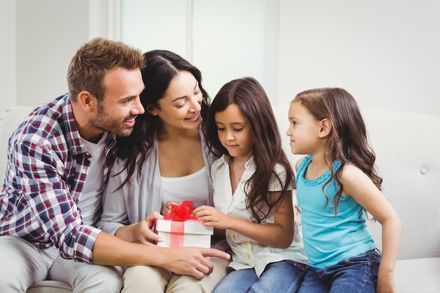 Happy parents with their daughters holding a gift box