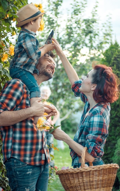 Happy parents with their little son kissing in nature in flowers