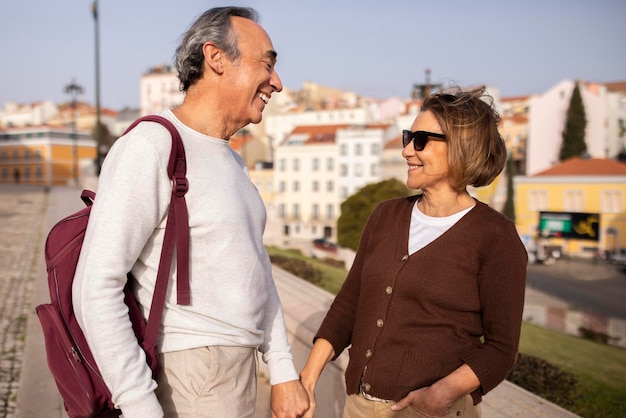 Happy pensioners couple holding hands walking with backpack outdoors