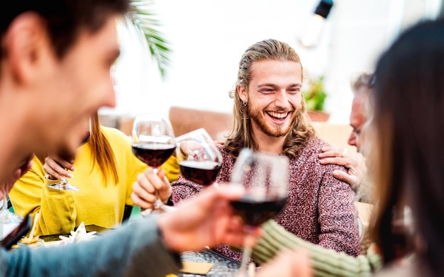 Happy people on genuine mood drinking red wine at rooftop party Millenial trendy friends having fun together at restaurant winery bar out side Dining life style concept with bright warm filter