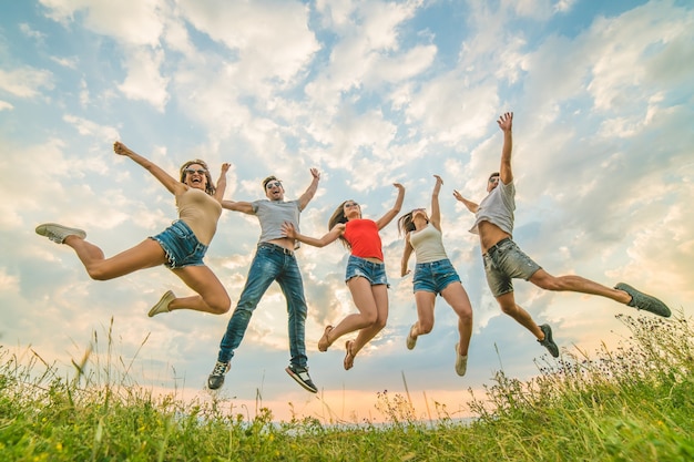 The happy people jumping on the background of the clouds