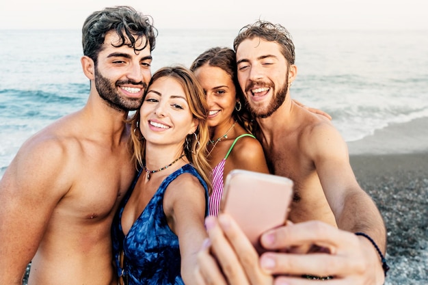 Happy people taking selfies on the beach lifestyle concept of happy friends on vacation using mobile phone to capture moment snapshot by the ocean