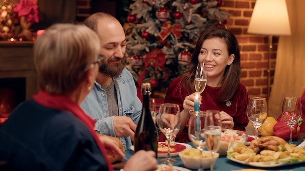 Happy people talking to each other while enjoying Christmas dinner at home. Festive joyful family members celebrating winter holiday while eating traditional home cooked food and chatting.