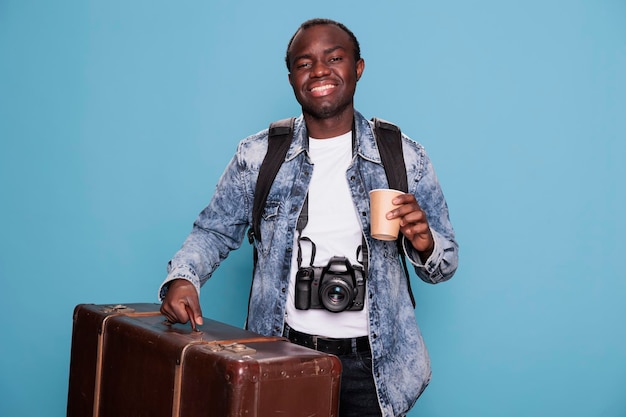 Happy photographer having luggage and DSLR camera getting ready for holiday journey. Joyful photography enthusiast with photo device and baggage going on weekend voyage trip.