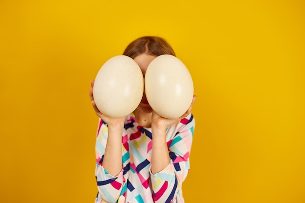 Happy playful teenager girl holding Ostrich eggs