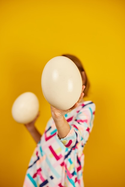 Happy playful teenager girl holding Ostrich eggs