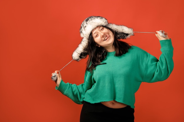 Happy plus size positive woman. Happy body positive concept. I love my body. Attractive overweight woman posing on camera in the studio on a colored background. Girl wearing a sweater and a winter hat