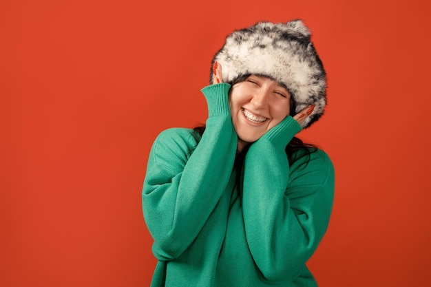 Happy plus size positive woman. Happy body positive concept. I love my body. Attractive overweight woman posing on camera in the studio on a colored background. Girl wearing a sweater and a winter hat