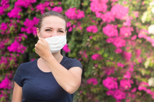 Happy positive girl, young beautiful woman takes off protective sterile medical mask