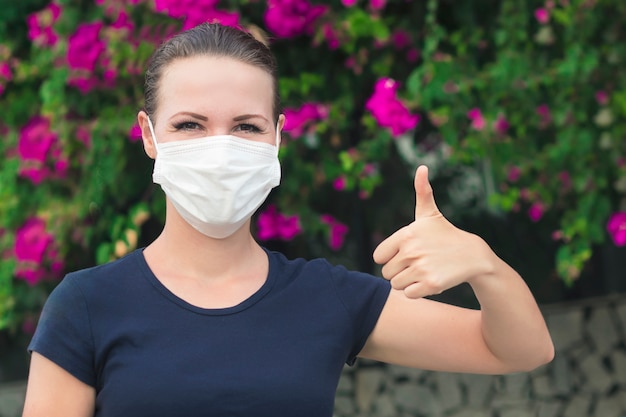 Happy positive girl, young cheerful beautiful woman in protective sterile medical mask on her face