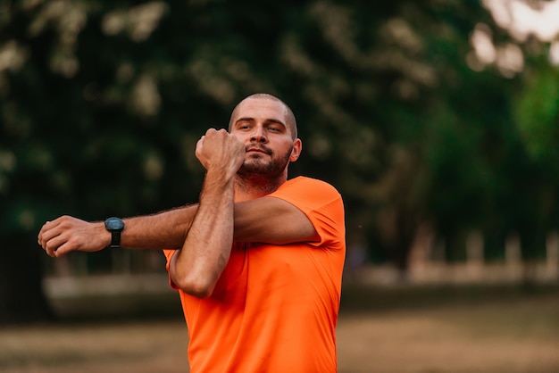 Happy positive sportsman during outdoor workout man wearing sports outfit warming up musclesenjoying active lifestyle outside in park