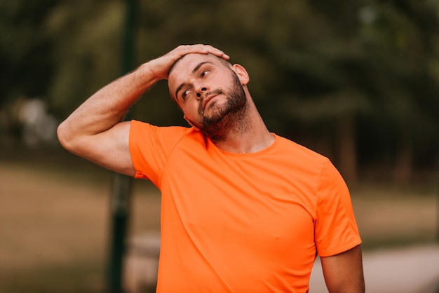 Happy positive sportsman during outdoor workout man wearing sports outfit warming up musclesenjoying active lifestyle outside in park