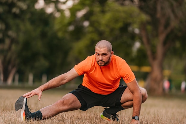 Happy positive sportsman during outdoor workout man wearing sports outfit warming up musclesenjoying active lifestyle outside in park