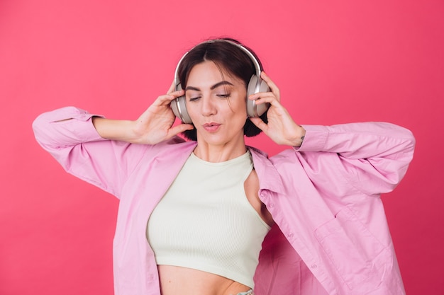 Happy positive woman in headphones on pink red wall