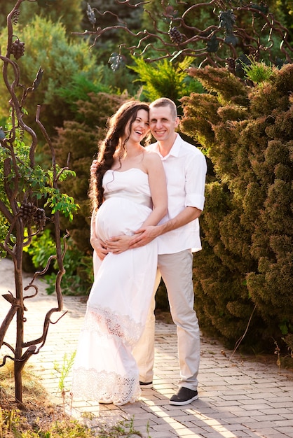 A happy pregnant couple is walking in nature.