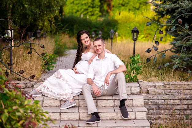 Happy pregnant couple with daughter touching belly in summer nature