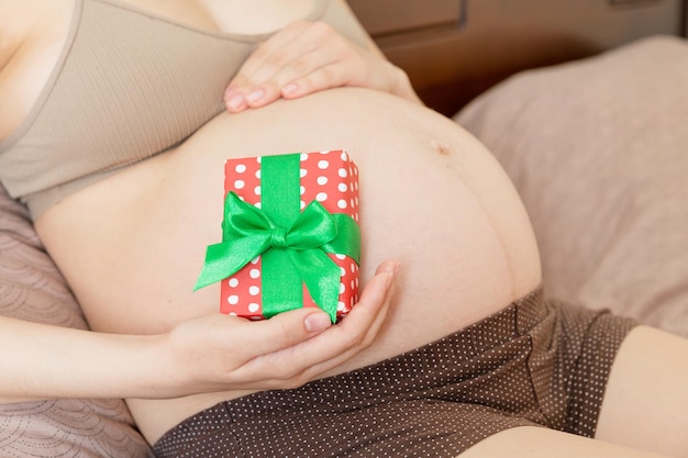 Happy pregnant woman holding Christmas gift box in her hands New year concept