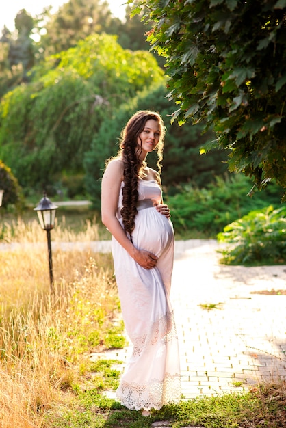 Happy pregnant woman smiles and hugs the belly.