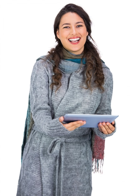 Happy pretty brunette wearing winter clothes holding her tablet